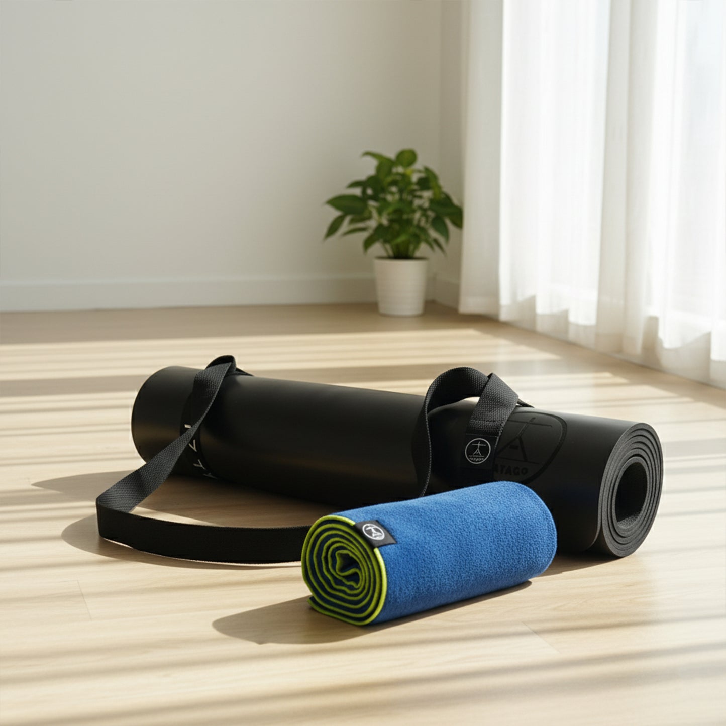 Black extra-large yoga mat with carry strap and blue hot yoga towel in studio