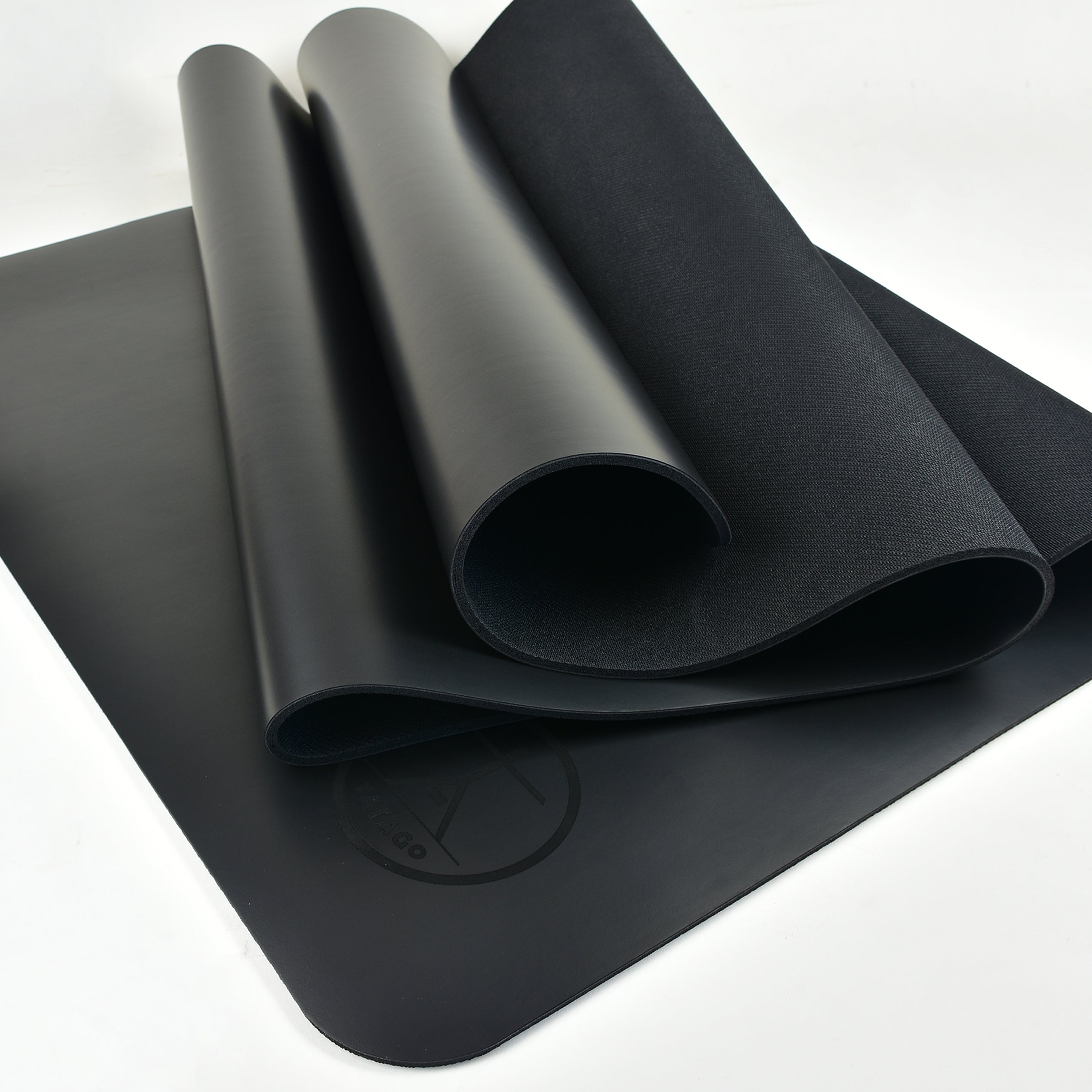 Black natural rubber yoga mat non skid rolled open, showing non-slip surface for hot yoga, Bikram, and Pilates