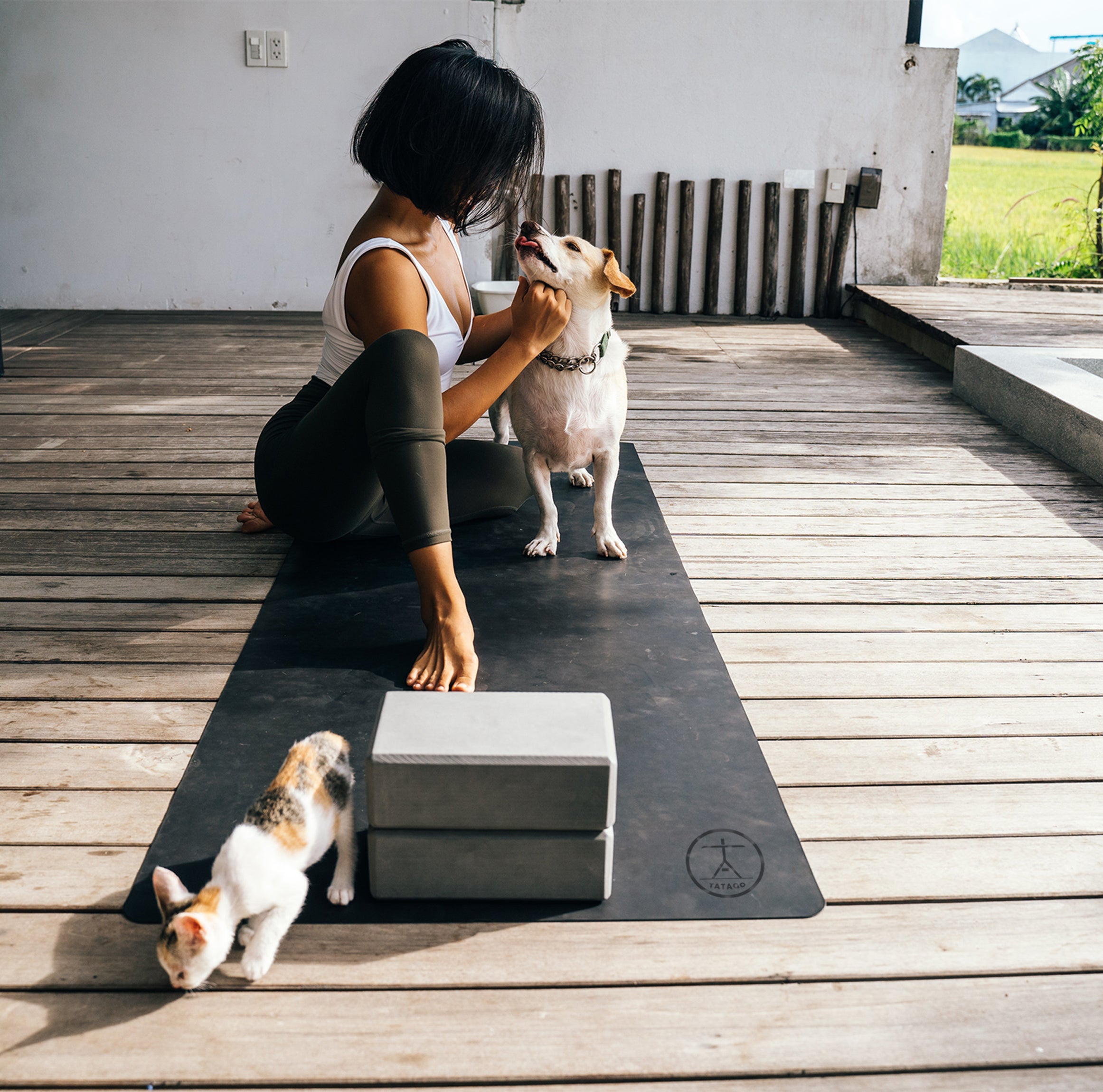Woman on warm yoga mat at home with pets, one of the best yoga mats for hot yoga and daily stretching.