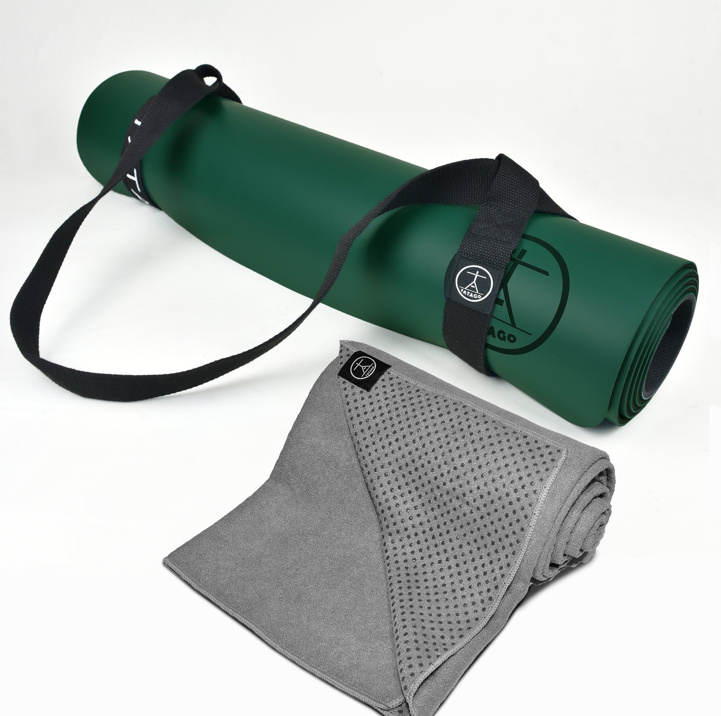 XL green natural rubber yoga mat with black carry strap paired with gray silicone-grip hot yoga towel for sweaty sessions