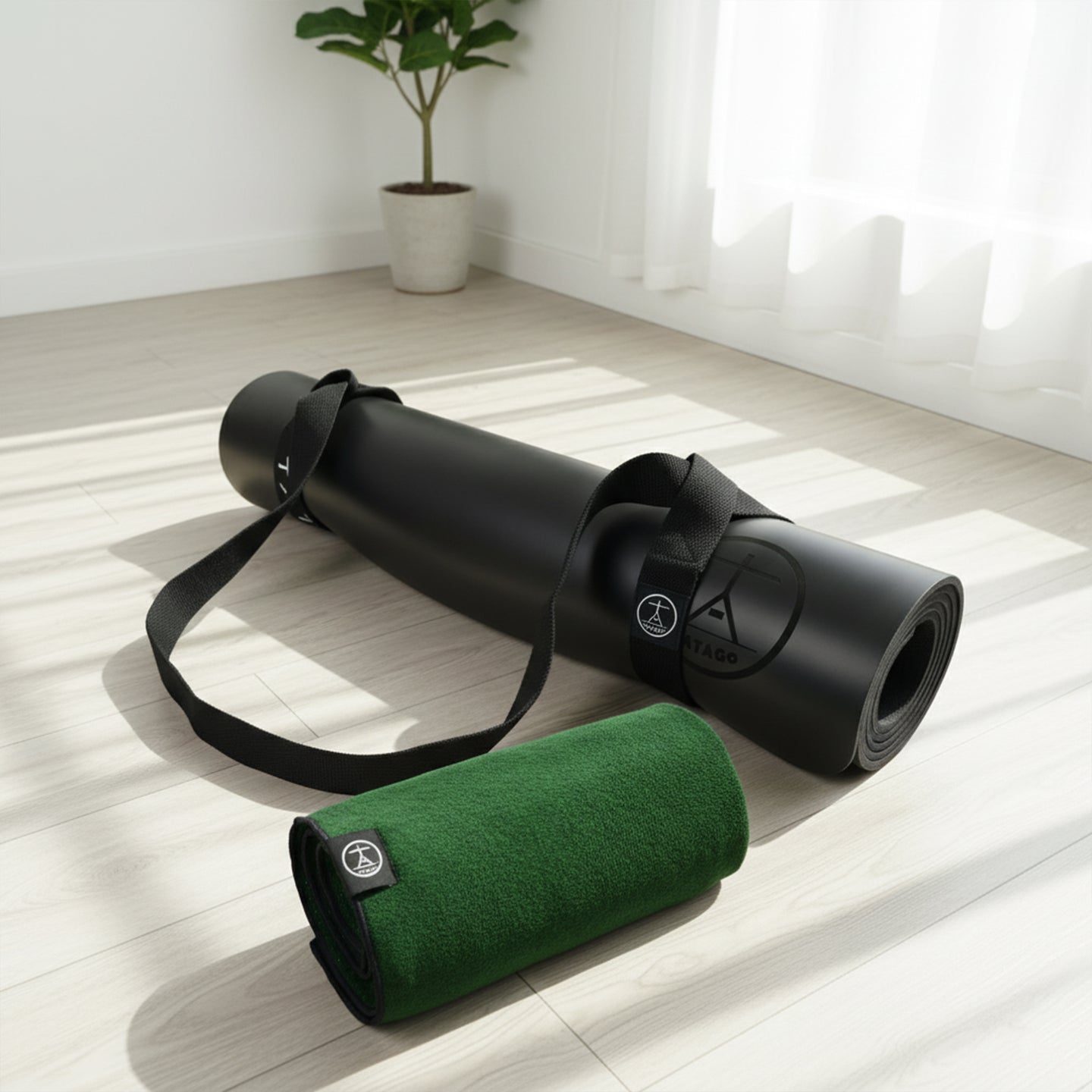 Black XL yoga mat with carry strap and rolled green hot yoga towel in a studio