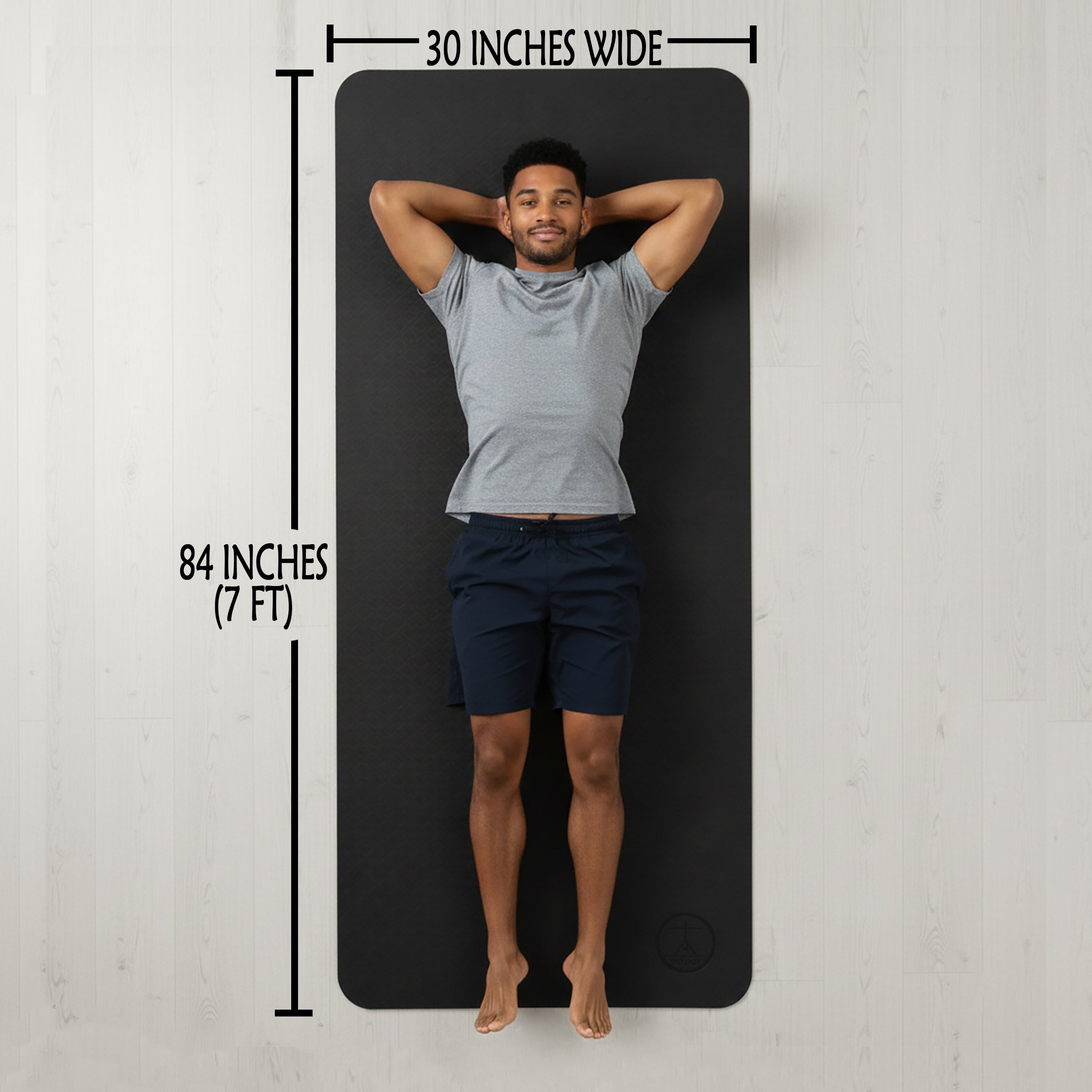 Man lying on extra large yoga mat showing 84 by 30 inch size