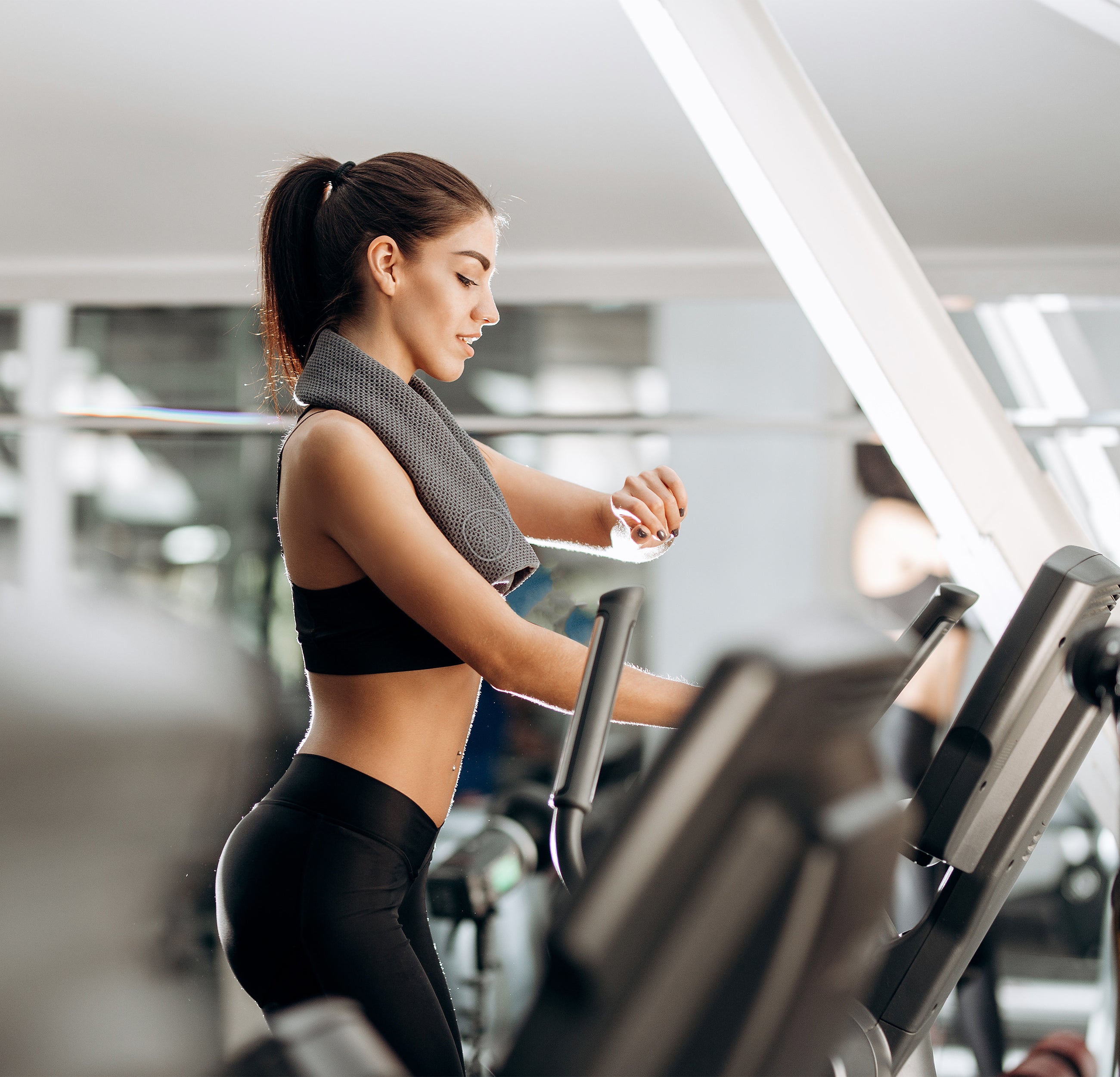 Fitness towel over the neck of a lady on a treadmill.