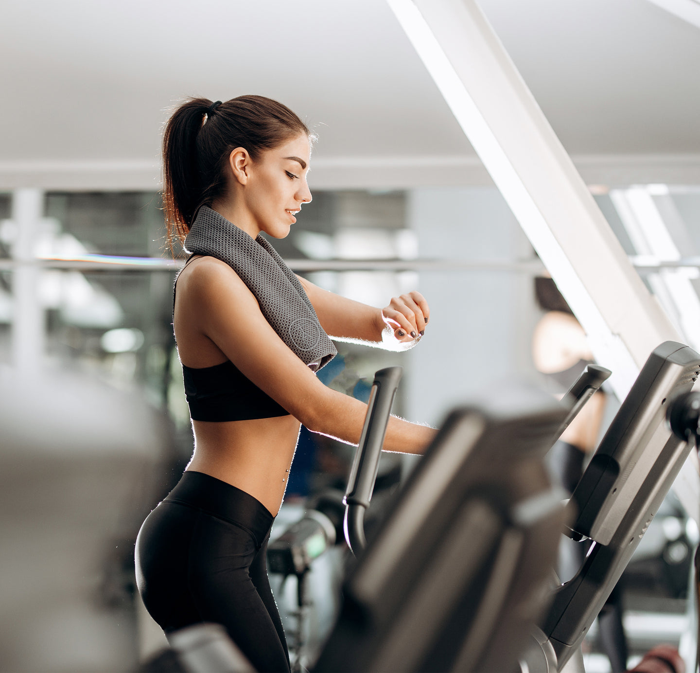 Fitness towel over the neck of a lady on a treadmill.