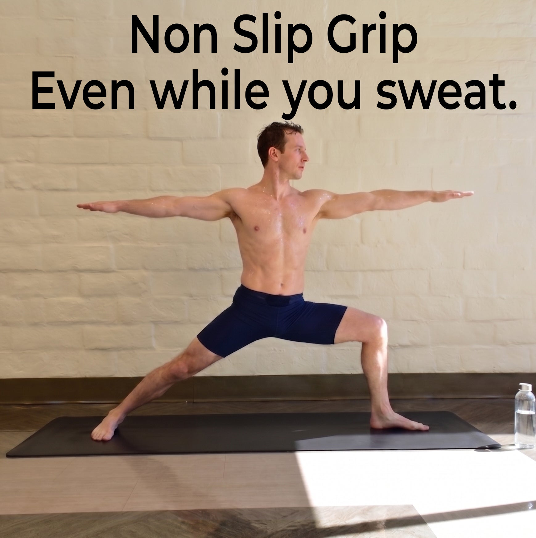 A shirtless man yoga pose on a black xl yoga mat in a studio, showing non-slip grip on the yoga mat.