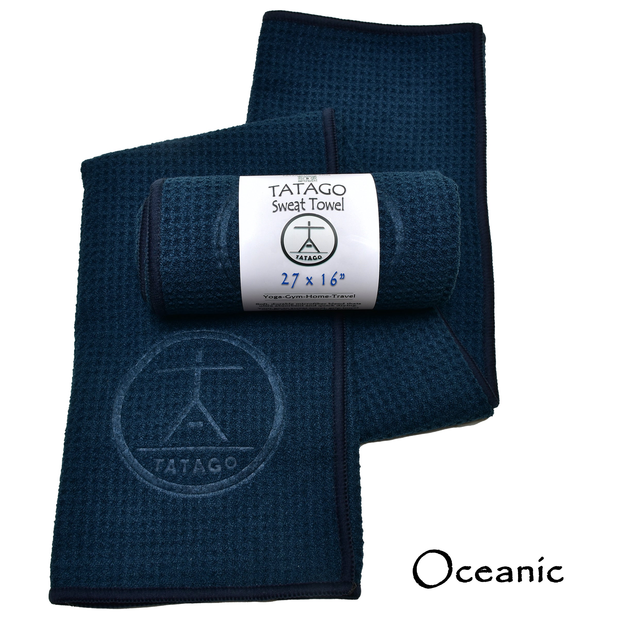 A navy blue microfiber yoga sweat towel with waffle texture, branded with the TATAGO logo, wrapped around a rolled towel, with the label 'Oceanic' visible.