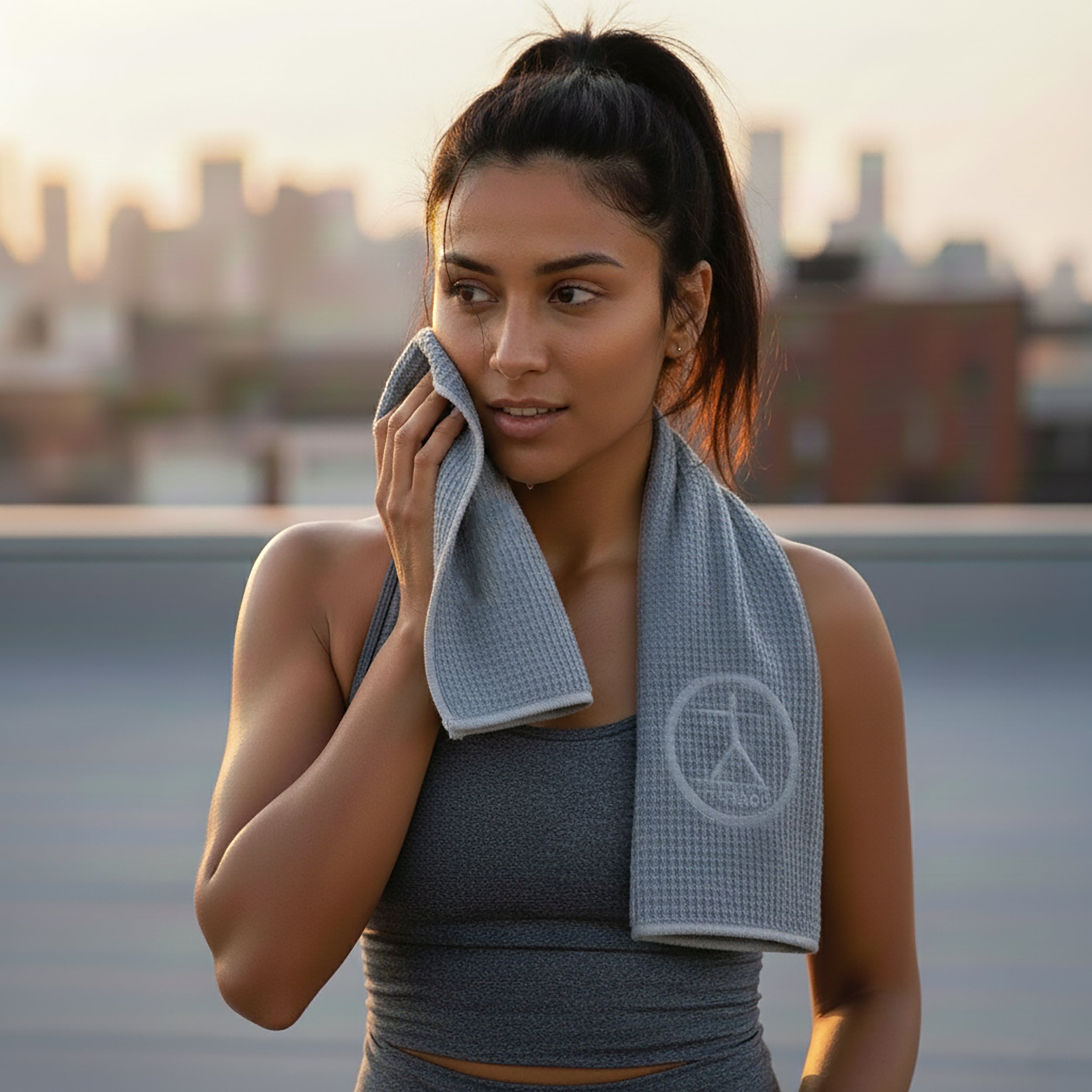 Woman holding a gray sweat towel wiping sweat from her face outdoors. (
Storm Gray)