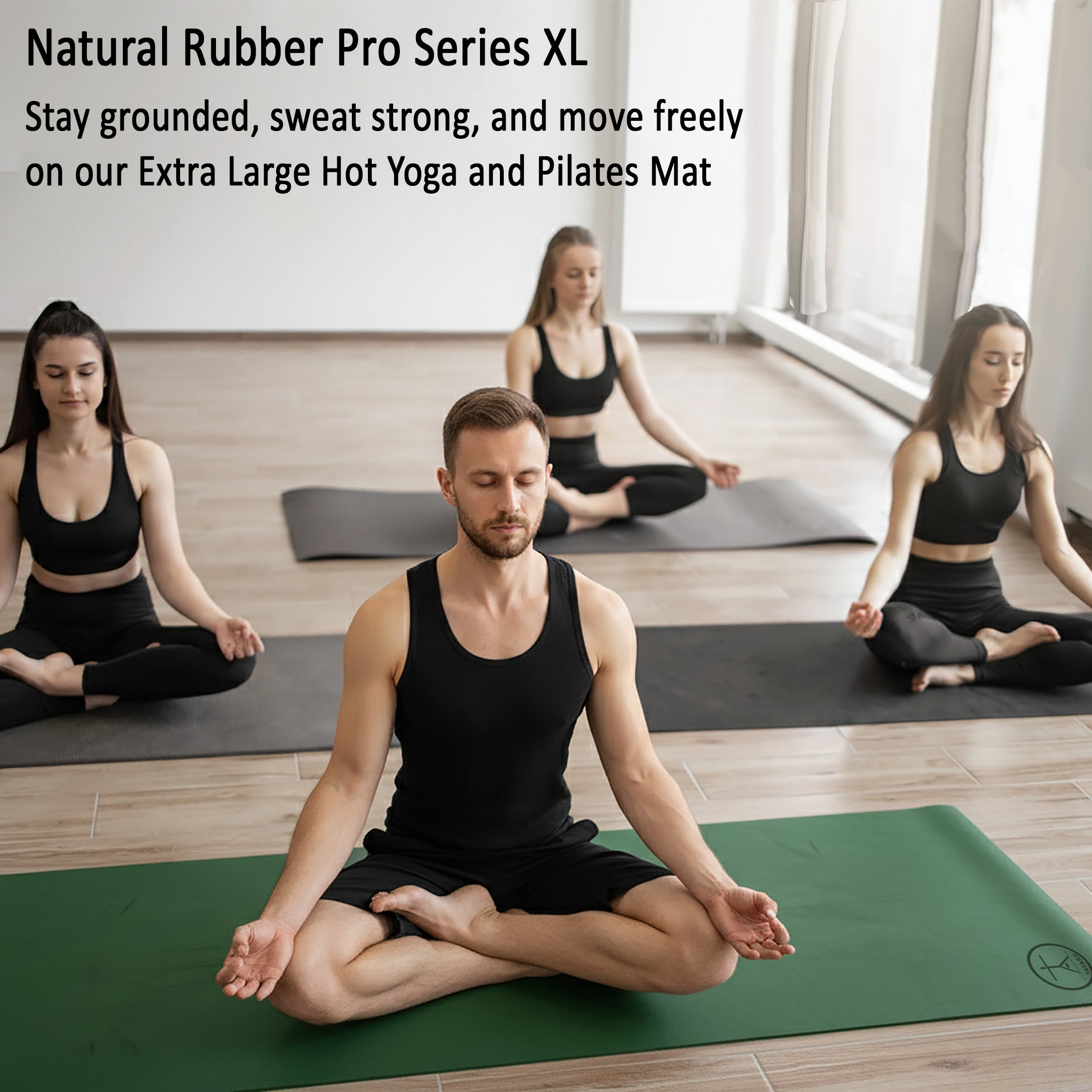 Yoga mat natural rubber design with man meditating on extra large non-slip mat during a studio hot yoga and Pilates session.