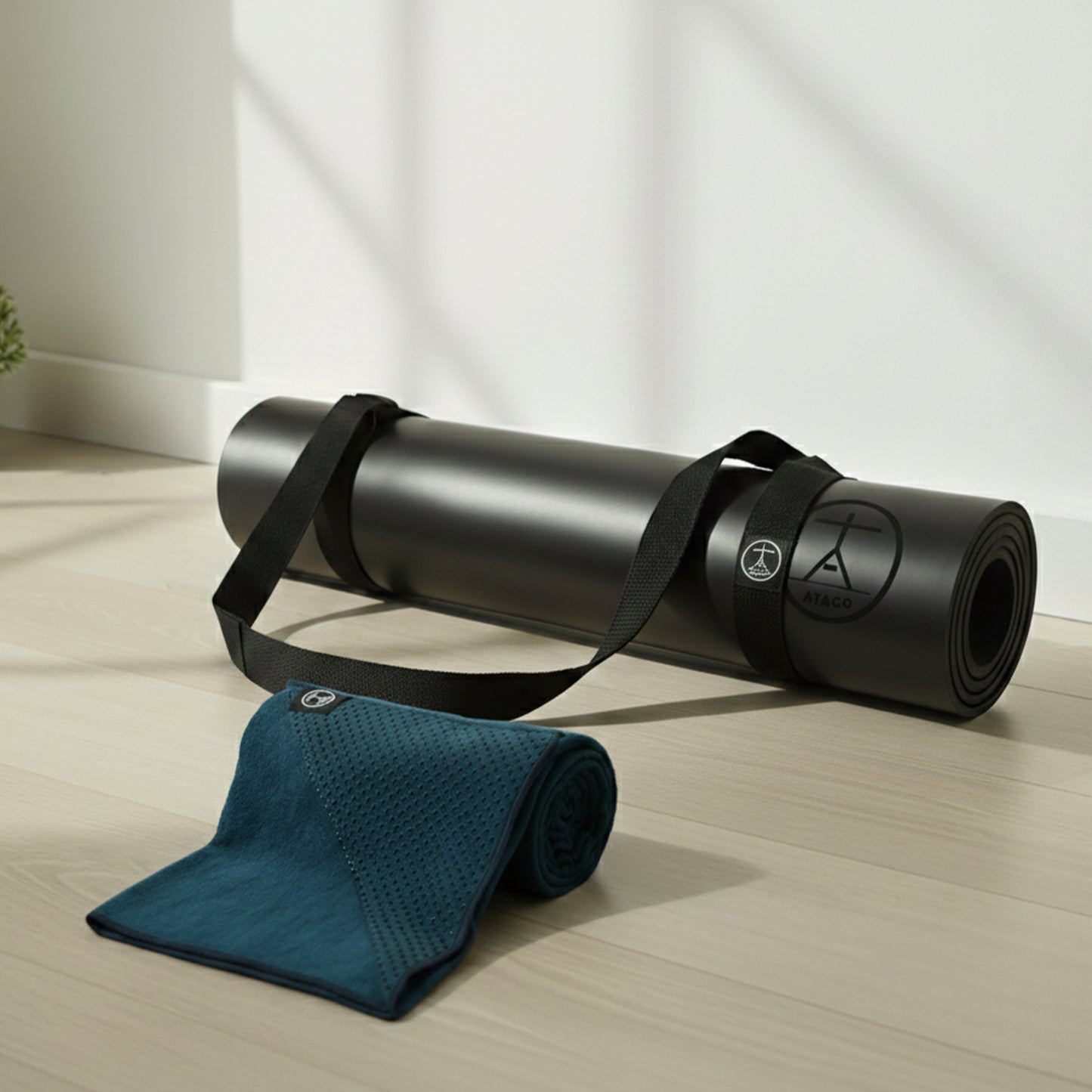 Natural rubber yoga mat with yoga strap and microfiber sweat towel displayed in a home yoga space, ideal for hot yoga, warm yoga, Pilates, and sweaty practice sessions.