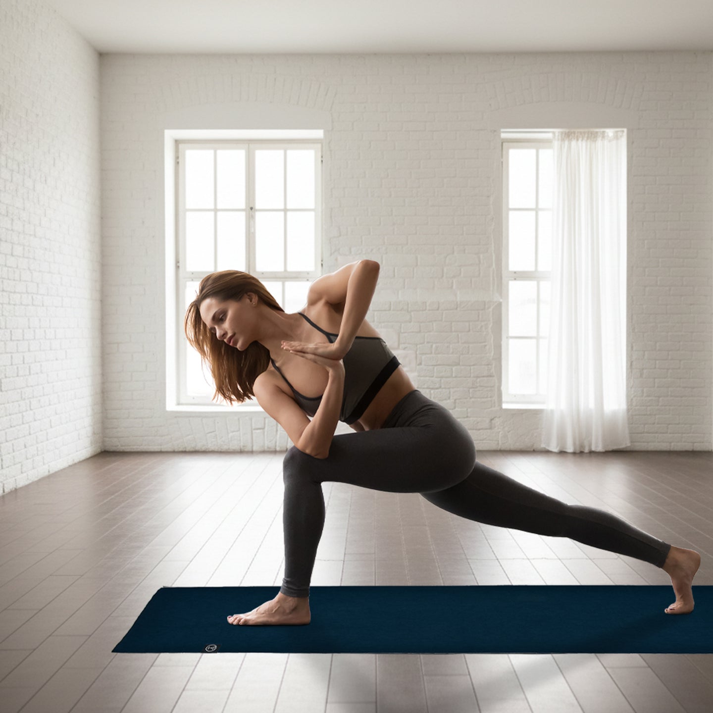Woman practicing a twisting lunge on a natural rubber yoga mat with strong traction for hot yoga, warm yoga, and Pilates stability training.
